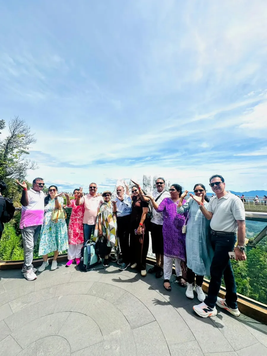 A returning travelling party waving from a stone viewing terrace above the Vietnamese coast