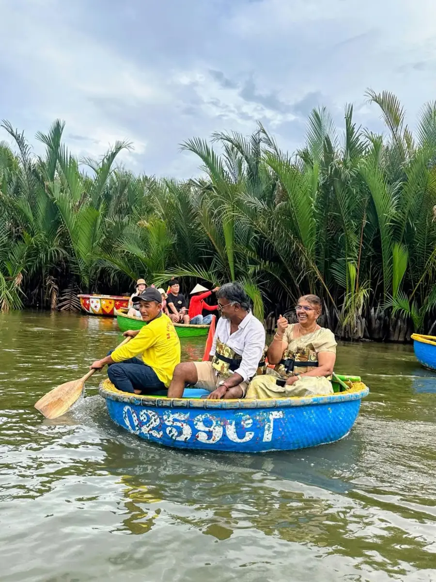 Travellers and their rower in a round bamboo basket boat among the water coconut palms at Hoi An, Vietnam