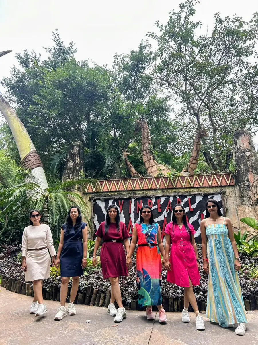 Six travellers on a garden path in front of a decorated wall at a park in Vietnam